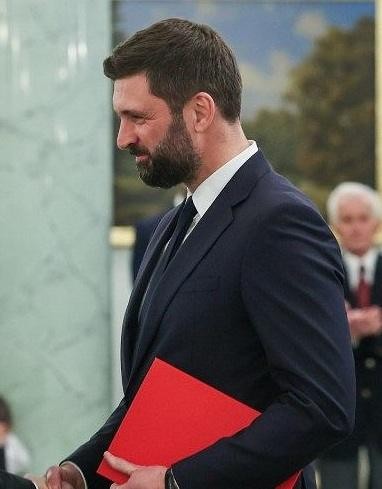 Nikodem Rachoń w swoim gabinecie w Kancelarii Prezydenta RP, otoczony symbolami polityki międzynarodowej.