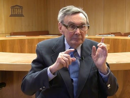 Dłonie Mariana Turskiego, naznaczone historią, spoczywające na księdze.