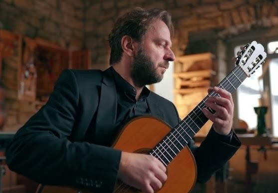 Dłonie Marcina Dylli grające na gitarze klasycznej.