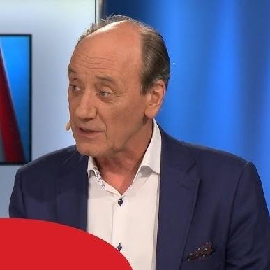 Budka komentatorska podczas meczu piłki nożnej, z widocznym mikrofonem i ekranem telewizora.