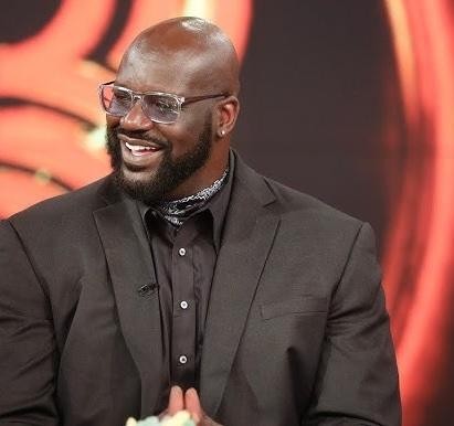 Shaquille O'Neal, w barwach Los Angeles Lakers, wykonuje efektowny dunk podczas meczu NBA, pokazując swoją siłę i dominację.