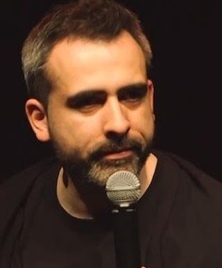 Abelard Giza w swobodnej, naturalnej pozie, z przyjaznym uśmiechem patrzący w obiektyw.