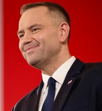 Karol Nawrocki, prezes IPN, w otoczeniu symboli historii i współczesności.