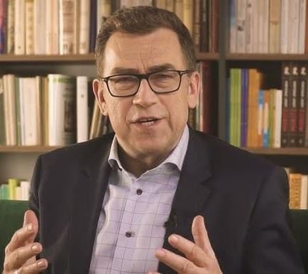 Maciej Orłoś, polski prezenter i aktor, uśmiechnięty, w ciepłym kadrze.