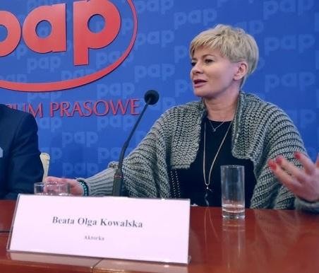Beata Olga Kowalska, polska aktorka, w uśmiechniętym portrecie na tle teatralnym.