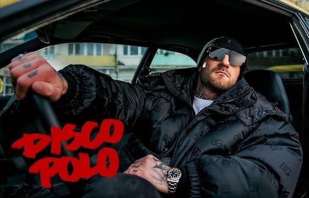 Kizo w dynamicznym kadrze podczas występu lub pracy w studio, emanujący energią i charyzmą, z subtelnymi nawiązaniami do jego wszechstronnej kariery.